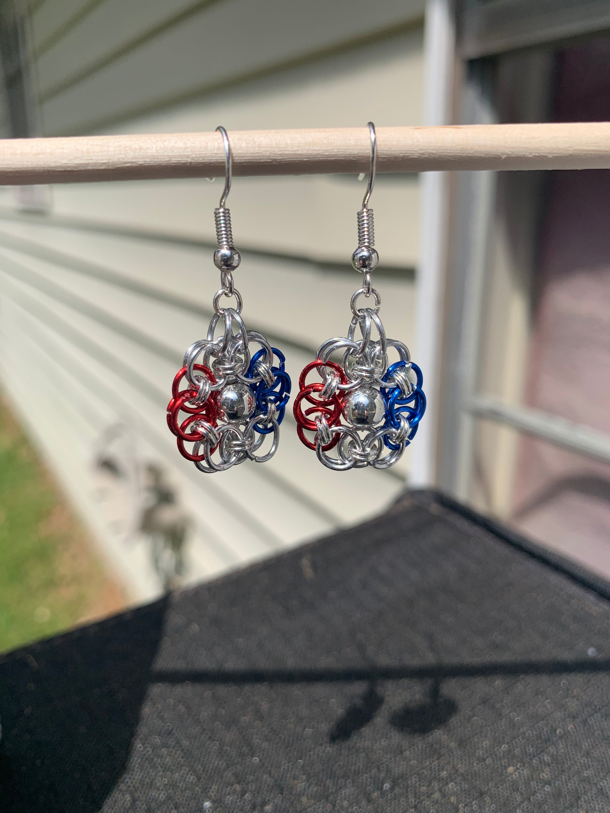 Show your patriotism with this USA-themed chainmail daisy boasting a silver bead in its center to emphasize and preserve the iconic red, white, and blue colors. The anodized aluminum can be equipped with either a silver fishhook or a silver stud upon request.